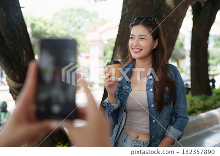 Bright Smiles. A young woman enjoying coffee while posing for a photo outdoors. 132357890