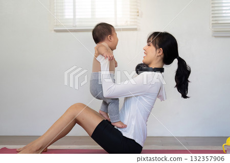 Activity and Engagement. A mother exercising and lifting her baby, blending fitness with quality time together. Activity and Engagement. A mother exercising and lifting her baby, blending fitness with quality time together. 132357906