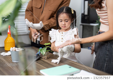 Child Learning and Gardening. A little girl prepares to help her parents with a plant care task. 132357937