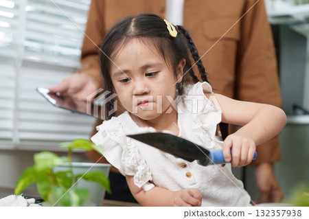 Gardening and Sustainability. A young child learns about caring for plants, demonstrating sustainable gardening practices. 132357938