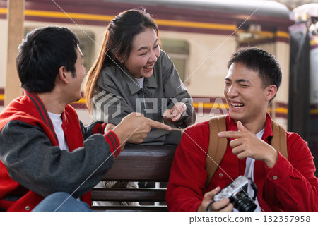 Laughter and Connection. Friends share a lighthearted moment while waiting at the train station. Laughter and Connection. Friends share a lighthearted moment while waiting at the train station. 132357958