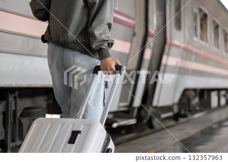 Travel and Journey. A traveler closely following a train, ready to board with a suitcase in tow. Travel and Journey. A traveler closely following a train, ready to board with a suitcase in tow. 132357963