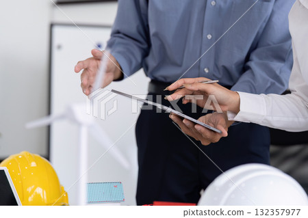 Engineering Collaboration for Sustainability. Engineers evaluating sustainable technology on a tablet during a project meeting. Engineering Collaboration for Sustainability. Engineers evaluating sustainable technology on a tablet during a project meeting. 132357977