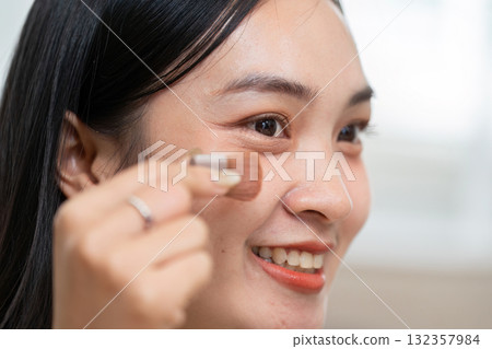 Skincare and Empowerment. A woman applying bronzer to enhance her features with joy. Skincare and Empowerment. A woman applying bronzer to enhance her features with joy. 132357984