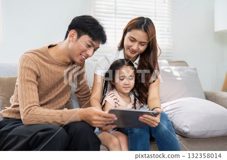 Family Time and Learning Together. A family shares a delightful moment watching a tablet, engaging in educational activities. 132358014