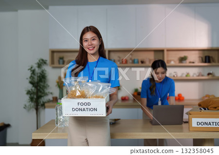 Food Donation Drive. Volunteer proudly holds food donation box in community center. Food Donation Drive. Volunteer proudly holds food donation box in community center. 132358045