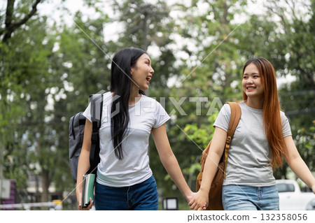 Friendship and Campus Life. Two girls walk hand in hand, sharing laughter on a school campus. 132358056