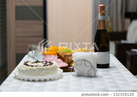 Festive table with a delicious cake, champagne, and snacks prepared for a celebration, symbolizing joy, hospitality, and special family or holiday moments 132358120