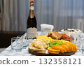 Elegant dinner table set with champagne, cheese, meat, and fruit slices, symbolizing celebration, hospitality, and the joy of sharing food and special moments 132358121