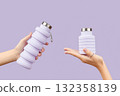 Womans hand holding collapsible reusable lilac water bottle on purple background. Zero waste 132358139