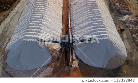 Aerial top view of massive salt piles and conveyor system at a salt production facility near Santa Pola, Spain. 132358948