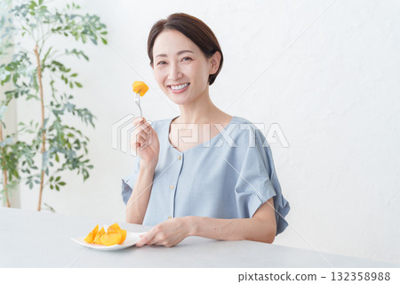 A woman eating persimmon fruit 132358988