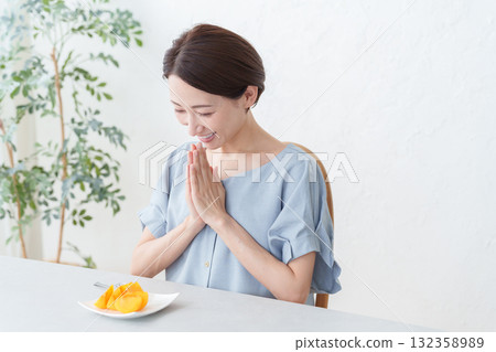 A woman eating persimmon fruit 132358989