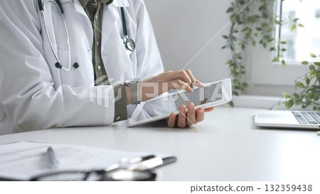 Female doctor in lab coat and stethoscope using digital tablet at desk in medical office, accessing online patient information. Medicine and health care concept Female doctor in lab coat and stethoscope using digital tablet at desk in medical office, accessing online patient information. Medicine and health care concept 132359438