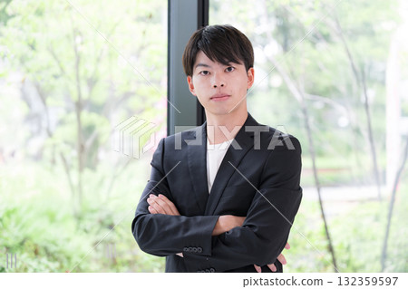 A young man in his twenties wearing a suit thinking with his arms crossed A young man in his twenties wearing a suit thinking with his arms crossed 132359597