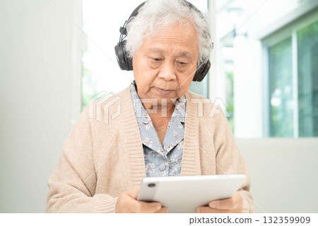 Asian senior woman patient happy to use earphone to listen relax music. 132359909