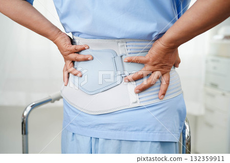 Asian senior pain back wearing elastic support belt with walker. 132359911