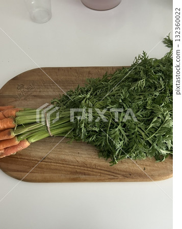 Fresh carrots with leafy green tops still attached, showcasing vibrant orange roots and crisp, earthy texture. offering a perfect blend of natural beauty, nutrition, and farm-fresh appeal in every gla Fresh carrots with leafy green tops still attached, showcasing vibrant orange roots and crisp, earthy texture. offering a perfect blend of natural beauty, nutrition, and farm-fresh appeal in every gla 132360022
