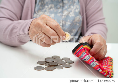 Asian senior or elderly old lady woman holding counting coin money in bag. Poverty, saving problem in retirement. 132360079
