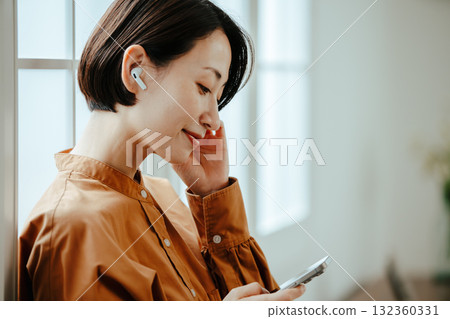 A woman in her 40s wearing wireless earphones A woman in her 40s wearing wireless earphones 132360331