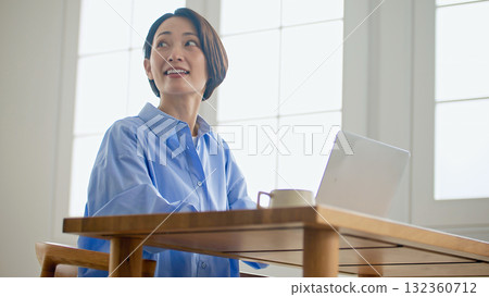 A woman using a computer is spoken to 132360712