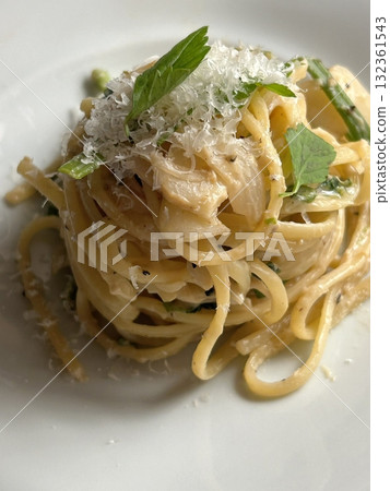Creamy and rich spaghetti coated in a luscious white sauce, offering a smooth and savory flavor perfect for a comforting and satisfying meal. 132361543