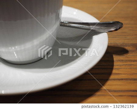 咖啡桌沐浴在透過樹梢的陽光下_用白瓷杯和湯匙享受溫馨的時刻 咖啡桌沐浴在透過樹梢的陽光下_用白瓷杯和湯匙享受溫馨的時刻 132362139