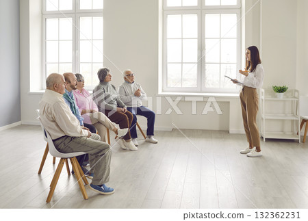 Group of senior men and women listening to lecture by psychologist or business coach Group of senior men and women listening to lecture by psychologist or business coach 132362231