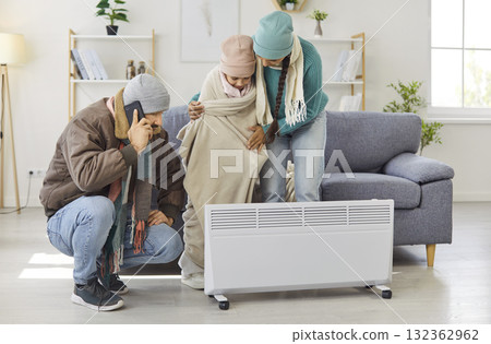 Phone call to emergency heating repair service, freezing family warming by heater Phone call to emergency heating repair service, freezing family warming by heater 132362962