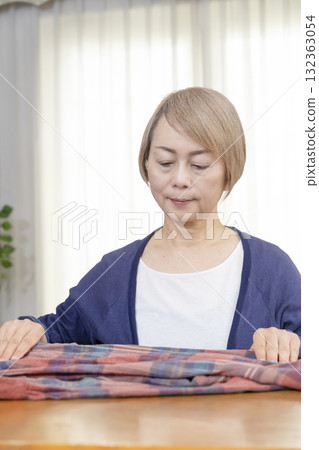 A senior woman packing unwanted clothes in the living room to sell them on a flea market site 132363054