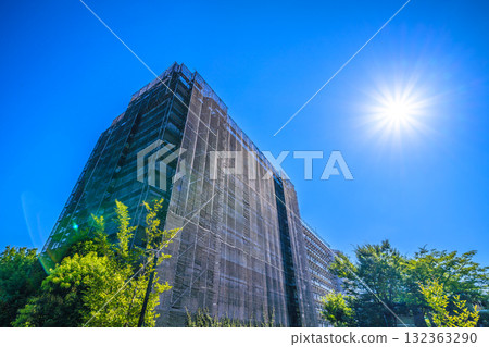 日本橫濱的城市景觀：重現昔日光彩……陽光下，一棟正在維修的公寓大樓。鷹架、防護網和衛星天線。 132363290