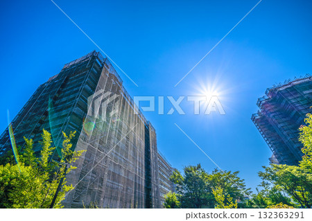 Yokohama cityscape in Japan: Restoring its brilliance... An apartment building under repair in the sunlight. Scaffolding, protective netting, and satellite antennas. Yokohama cityscape in Japan: Restoring its brilliance... An apartment building under repair in the sunlight. Scaffolding, protective netting, and satellite antennas. 132363291
