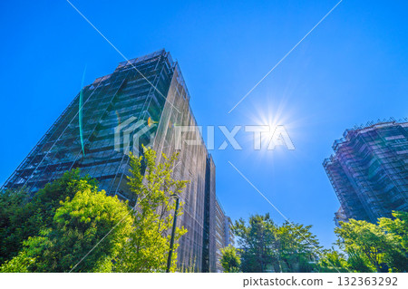 Yokohama cityscape in Japan: Restoring its brilliance... An apartment building under repair in the sunlight. Scaffolding, protective netting, and satellite antennas. Yokohama cityscape in Japan: Restoring its brilliance... An apartment building under repair in the sunlight. Scaffolding, protective netting, and satellite antennas. 132363292