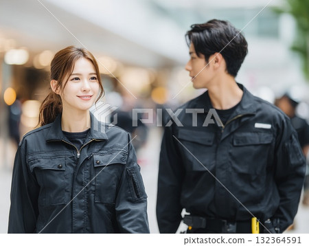 身著制服的微笑男女緊密站在一起，背景是城市景觀。 132364591