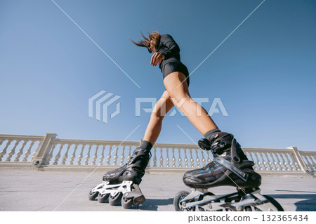 Low angle view of slim woman rollerblading on sunny day Low angle view of slim woman rollerblading on sunny day 132365434
