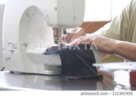 Woman using a sewing machine Woman using a sewing machine 132365480