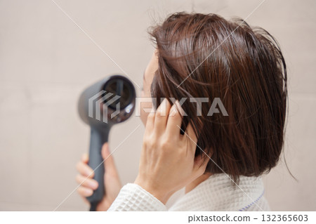 A woman using a hair dryer after taking a bath 132365603