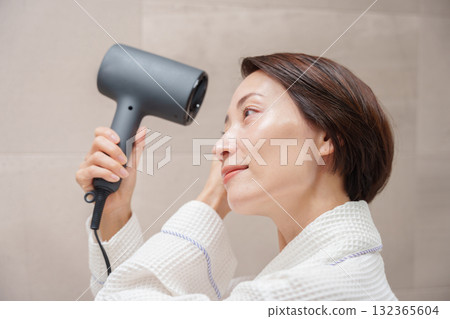 A woman using a hair dryer after taking a bath 132365604