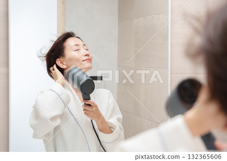 一位女士洗完澡後使用吹風機 132365606