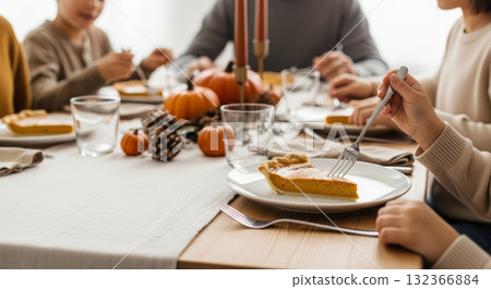 Family eating pumpkin pie at a cozy Thanksgiving dinner table. 132366884