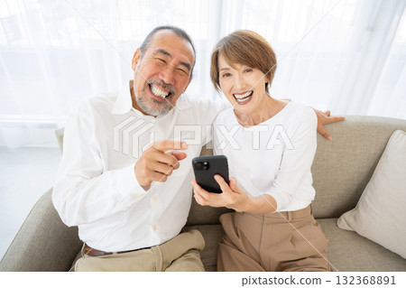 Senior couple laughing happily while operating a smartphone 132368891