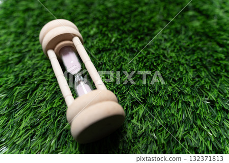 Wooden hourglass on the grass Wooden hourglass on the grass 132371813