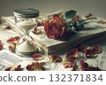 A still life with a fading rose lying on a stack of papers next to an hourglass 132371834
