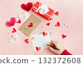 on pink background paper hearts, an envelope and a letter are written by a girl 132372608