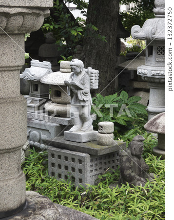 A stone statue carrying firewood on its back, surrounded by stone lanterns and standing in the greenery A stone statue carrying firewood on its back, surrounded by stone lanterns and standing in the greenery 132372750