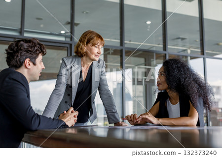 Confident businesswoman leading diverse team meeting in modern office, showcasing teamwork, leadership, communication and corporate collaboration in professional business environment. 132373240