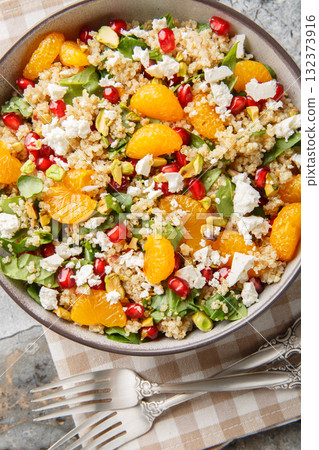 Winter Pomegranate Orange Quinoa Salad with spinach, feta, and pistachios closeup on the plate. Vertical top view 132373916