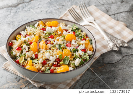 delicious, vitamin-rich quinoa salad with spinach, feta, tangerines, pomegranate, and pistachios, close-up in a bowl. Horizontal delicious, vitamin-rich quinoa salad with spinach, feta, tangerines, pomegranate, and pistachios, close-up in a bowl. Horizontal 132373917