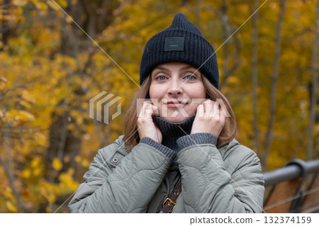 Authentic autumn portrait of a young woman in cozy outerwear enjoying nature in Moscow park. Fashion, mindfulness, and sustainable living concepts 132374159