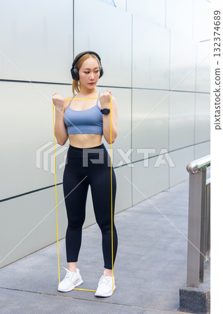 Fit woman performs sport exercise workout outdoor, using resistance band for arm stretch, developing fit physique, people pursue fitness goals Fit woman performs sport exercise workout outdoor, using resistance band for arm stretch, developing fit physique, people pursue fitness goals 132374689